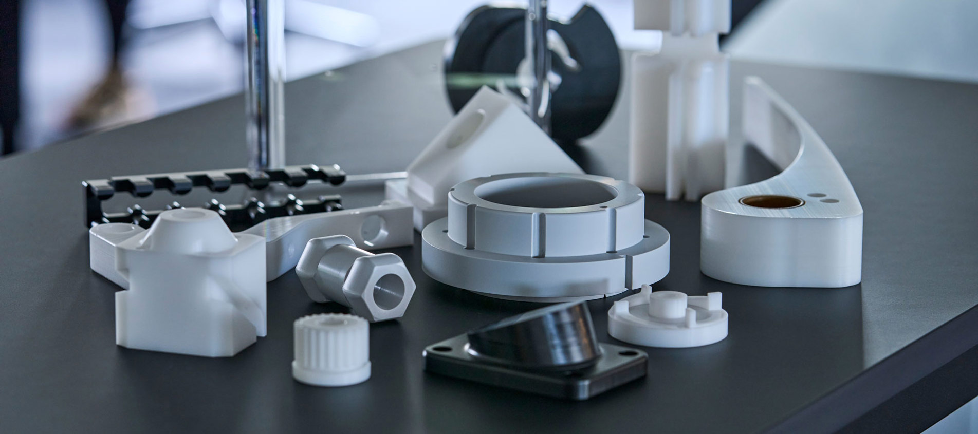 Machine parts of engineering plastics in the colours grey, white and black.