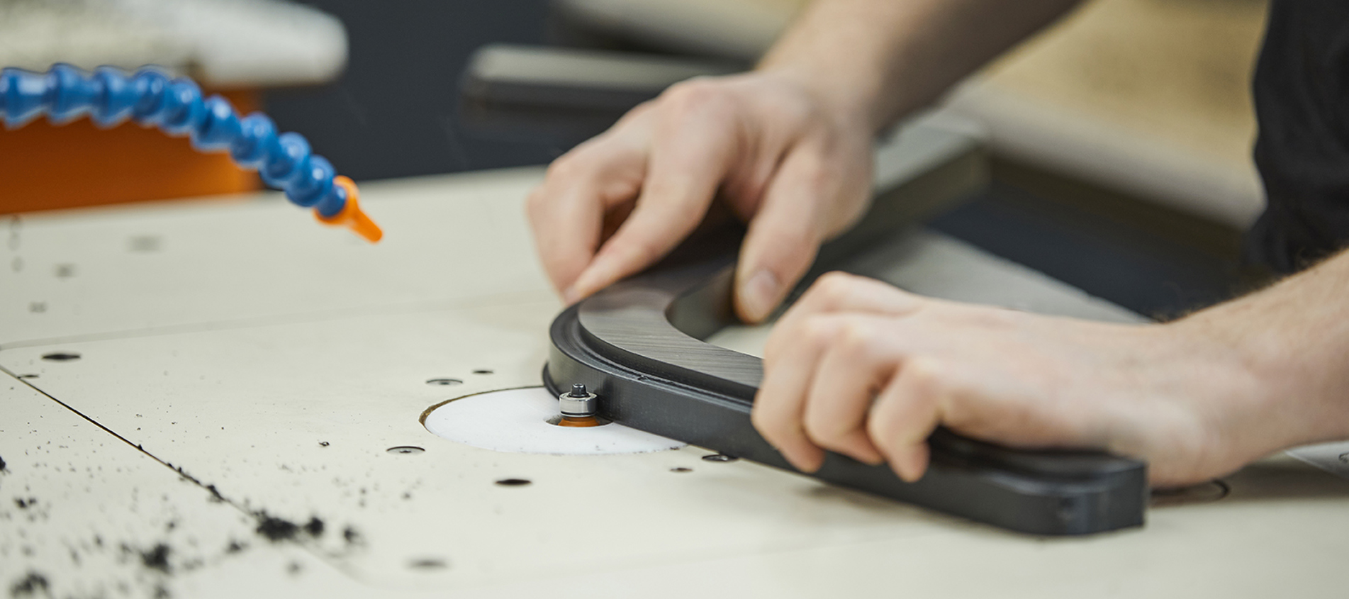 Production employee at Induflex deburring a plastic part in black POM